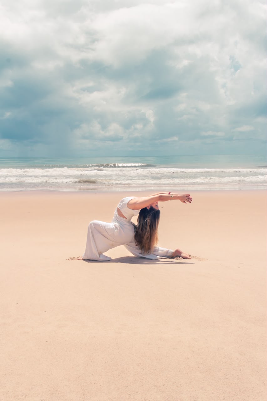 Madu em postura de yoga na areia, diante do mar